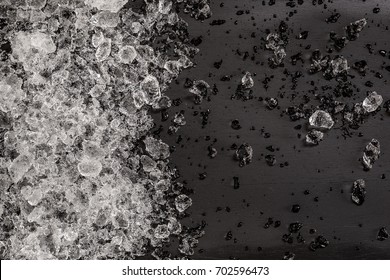 Crushed ice cubes on vintage black wooden table. Top view.