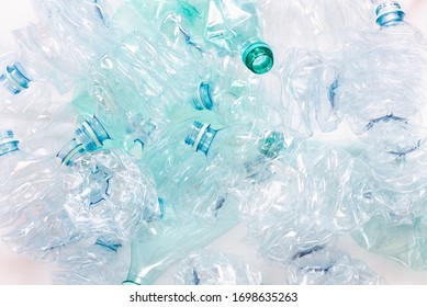 Crushed Plastic Bottles On Light Background. A Symbol Of Environmental Pollution And Recycling Challenges And Successes