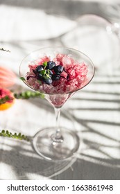 Crushed Red Ice In Martini Glass. Berry Granita With Mint And Blueberries. Harsh Light And Shadows. Natural Lighting. White Background. Sunlight With Large Shadows. Minimalist Food Photography.