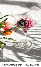 Crushed Red Ice In Martini Glass. Berry Granita With Mint And Blueberries. Harsh Light And Shadows. Natural Lighting. White Background. Sunlight With Large Shadows. Minimalist Food Photography.