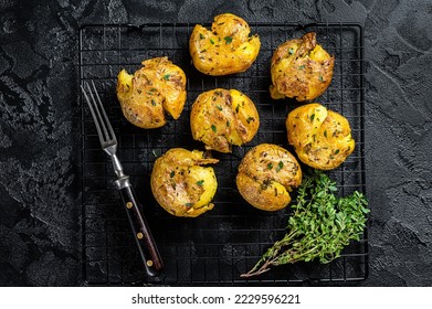 Crushed, smashed potatoes baked with rosemary and thyme. Black background. Top view.