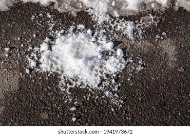 A Crushed Snowball With An Imprint Of The Sole On The Asphalt. Melting Snow In Spring