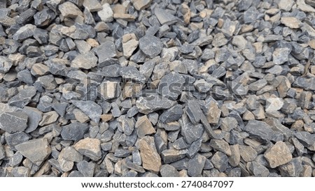 Crushed stone aggregate features sharp angular blue gray and tan pieces filling the frame creating a rugged and durable natural background texture for industrial or landscaping applications.