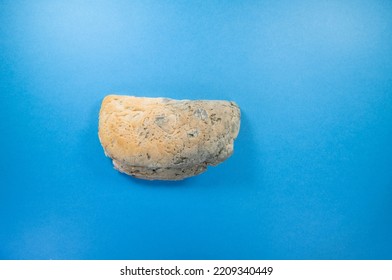 crust end of a seeded loaf with blue mould isolated on a dark blue background - Shutterstock ID 2209340449