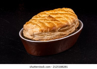 A Crusty British Pub Fare Steak And Kidney Pot Pie In A Brown Casserole Dish On A Black Table