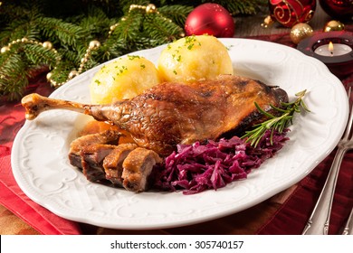 Crusty Goose Leg With Braised Red Cabbage And Dumplings On Christmas Decorated Table