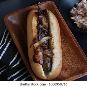 Crusty Roll With Sausage And Braised Onions On Wooden Tray