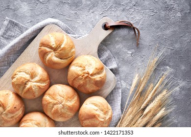 Crusty round bread rolls, known as Kaiser or Vienna rolls on linen towel, flat lay on rustic background
