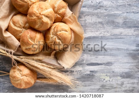 Crusty round bread rolls, known as Kaiser or Vienna rolls on linen towel, flat lay on rustic background with text space