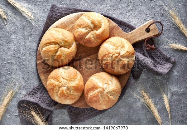 Crusty round bread rolls,\
known as Kaiser or Vienna rolls on linen towel, flat lay on rustic\
background