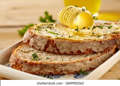 Crusty Slices Of Fresh Buttered Rye Bread Garnished With Chopped Parsley And A Butter Curl In Close Up On A Plate Or Tray