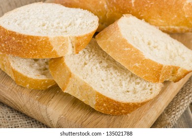 Crusty slices of white bread on a wooden chopping board.