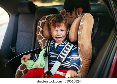 Crying baby boy in car seat.