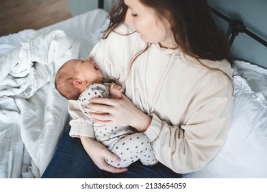 Crying Baby Girl On Mother Hands With Colic Stomach Ache In Bed. Health Care. Sick Infant Child With Woman At Home. Motherhood. 