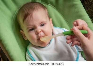 Crying baby girl refusing to eat food from spoon