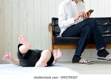 Crying Baby And Mother Using Smart Phone In Living Room