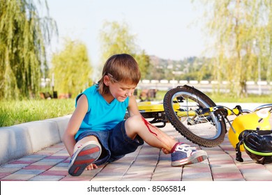 Crying Boy With A Bleeding Injury Sitting Beside The Bike That He Has Fallen From