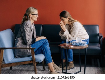 Crying depressed female client sitting on couch in therapist's workshop talking about trauma. - Powered by Shutterstock