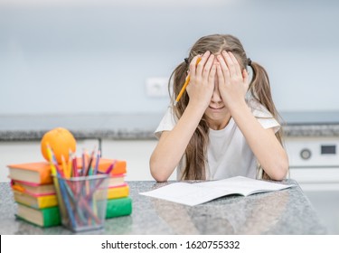 Crying little girl sits with homework at home and covers her face with her hands. Empty space for text - Powered by Shutterstock