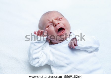 Crying newborn baby on changing table. Cute little girl or boy two weeks old. Dry and healthy body and skin concept. Baby nursery
