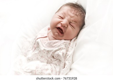 Crying newborn infant with closed eyes.