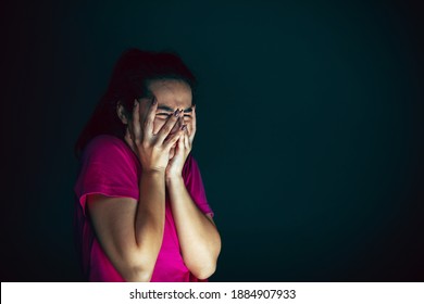 Crying. Portrait of young crazy scared and shocked caucasian woman isolated on dark background. Copyspace for ad. Bright facial expression, human emotions concept. Looking horror on TV, cinema.