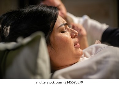 Crying Pregnant Woman Giving Birth At Home. Woman With Pierced Nose Lying, Feeling Contractions During Childbirth. Pregnancy, Home Birth Concept