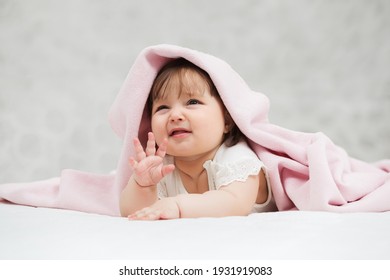Crying six months old baby girl lying on blanket at home