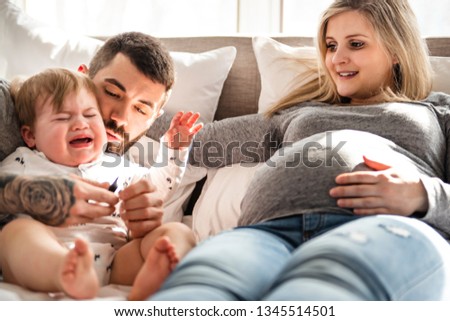 A crying son with parent in bed at home