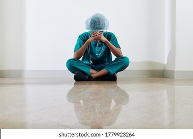 Crying Stressed And Tired Medical Nurse Sitting On Floor Of Hospital Hall After Long Day Of Work