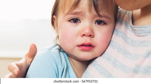 Crying toddler girl being consoled by her mother
