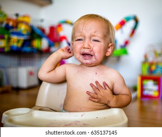 Crying Toddler Throws Temper Tantrum In Highchair With Food On Face