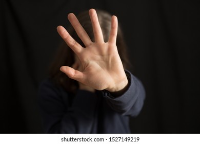 A crying woman covers her face with her hand on a black background. The concept of domestic violence. - Shutterstock ID 1527149219