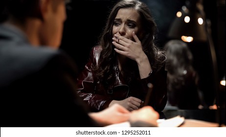 Crying Woman Smoking Cigarette In Interrogation Room, Giving Evidence To Cop