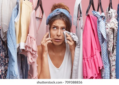 Crying Woman Wiping Her Face With Clothes While Standing Near Her Wardrobe, Calling Her Friend, Complaining That She Has Nothing To Wear And No Money For Buying New Outfit. People, Problems, Fashion