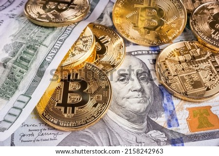 Crypto Bitcoin One dollar bitcoin, virtual money and one hundred dollar banknotes. Bitcoins on US dollars. Dollar to bitcoin exchange. Background with crypto bitcoins, and dollars. Golden bitcoin. 