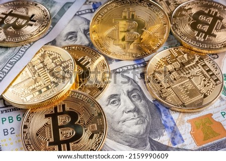 Crypto Bitcoin One dollar bitcoin, virtual money and one hundred dollar banknotes. Bitcoins on US dollars. Dollar to bitcoin exchange. Background with crypto bitcoins, and dollars. Golden bitcoin. 