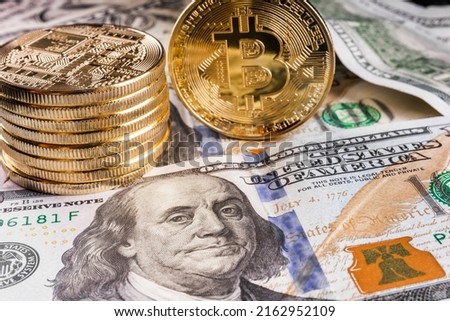 Crypto Bitcoin One dollar bitcoin, virtual money and one hundred dollar banknotes. Bitcoins on US dollars. Dollar to bitcoin exchange. Background with crypto bitcoins and dollars. Golden bitcoin