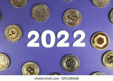 Cryptocurrency in 2022 price prediction, value forecast concept. Golden crypto coins Bitcoin, Uniswap, Nano, Tezos, Ankr, Chainlink next to the white year numbers on purple background.