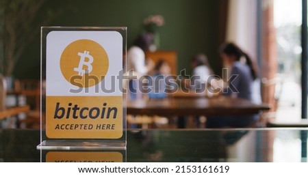 Cryptocurrency Bitcoin ethereum blockchain accepted sign logo on modern SME coffee shop table with defocus blurred background of customer eating enjoy meal. Virtual shopping digital money service.