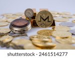  Cryptocurrency concept. Shining Monero cryptocurrency coin in front of five gold bars and by an old vintage pocket watch, isolated in white background. selective focus. 