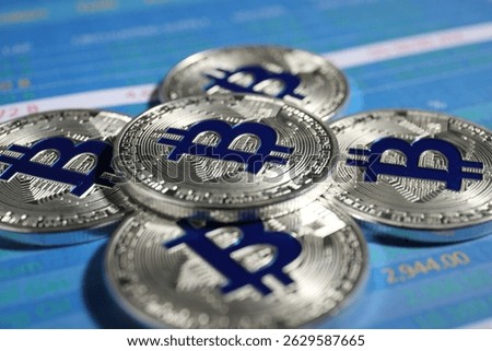 Cryptocurrency. Silver bitcoins on data charts, closeup