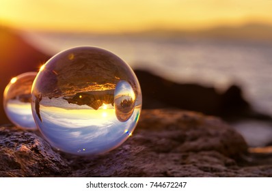 Crystal Ball Reflection On The Seashore In Sunrise Light. Mirror Reflections In Two Crystal Balls