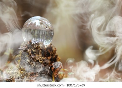 A Crystal Ball In The Smoke. A Magical Accessory In The Woods On The Stump. Ritual Ball Of Witches And Sorcerers On An Old Rotten Stump.