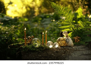 crystal balls, candles, moon amulet and magic bag on stump in forest, abstract natural background. occult esoteric spiritual ritual. witchcraft, wiccan magic. fairytale, mystery atmosphere.