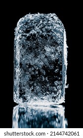 Crystal clear frosty textured natural ice block on black mirroring surface.