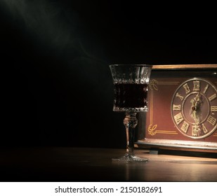 A Crystal Glass With An Old Golden Clock In A Narrow Beam Of Light In A Smoky Space With A Dark Background.