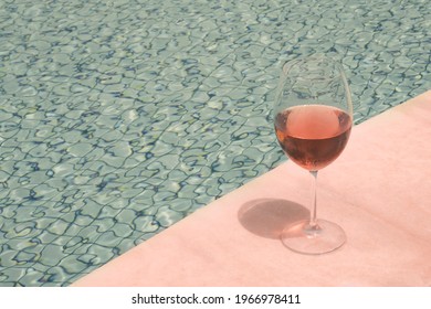 Crystal Goblet With Rose Wine On The Edge Of A Swimming Pool. High Class People Concept.