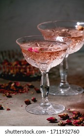 Crystal Vintage Glasses Of Pink Rose Champagne, Cider Or Lemonade With Dry Rose Buds. Grey Texture Background.