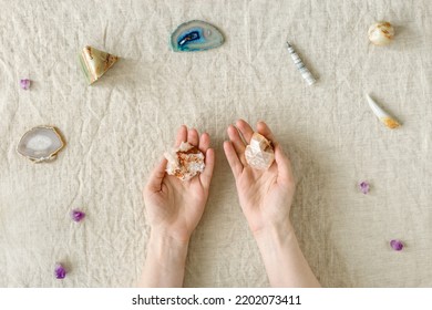 Crystals On Table, Woman Hand Holding Quartz, Healing Minerals Agate, Quartz, Amethyst, Onyx, Semiprecious Gem. Stones For Stone Therapy, Lithotherapy, Rock For Ritual. Top View Flat Lay With Daylight